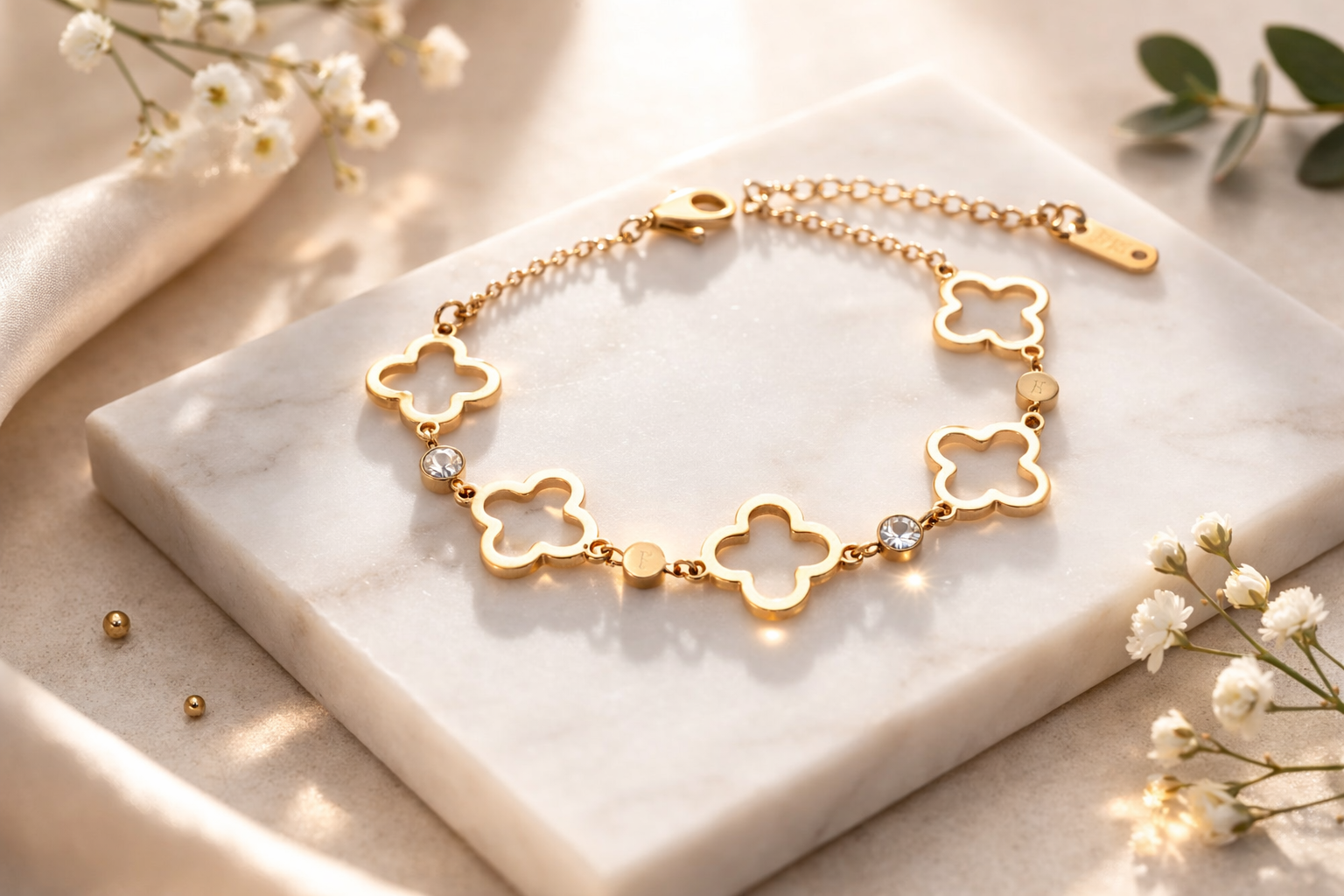 Gold bracelet with clover designs on a marble surface with flowers