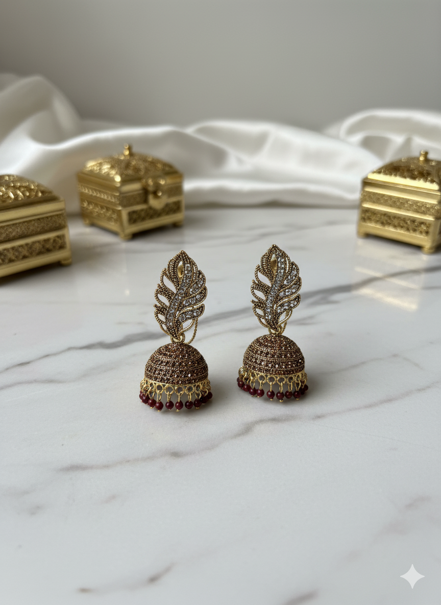 Gold-plated Pakistani Jhumka earrings with white stone leaf and maroon bead drops.