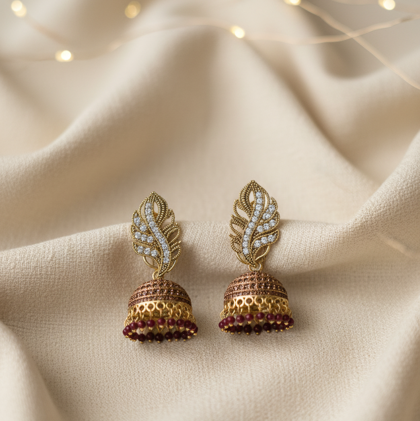 Gold-plated Pakistani Jhumka earrings with white stone leaf and maroon bead drops.
