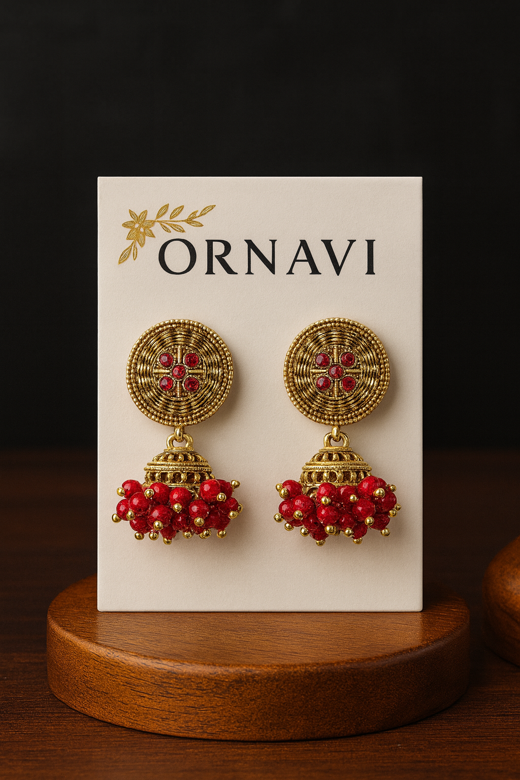 Gold and red earrings on an ORNAVI branded card with a dark background