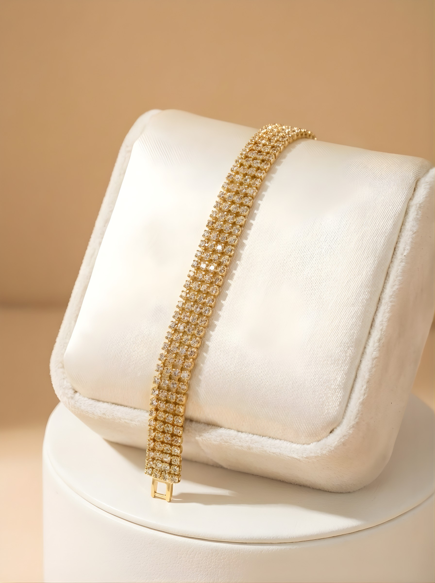 Gold bracelet on a white cushion with a beige background