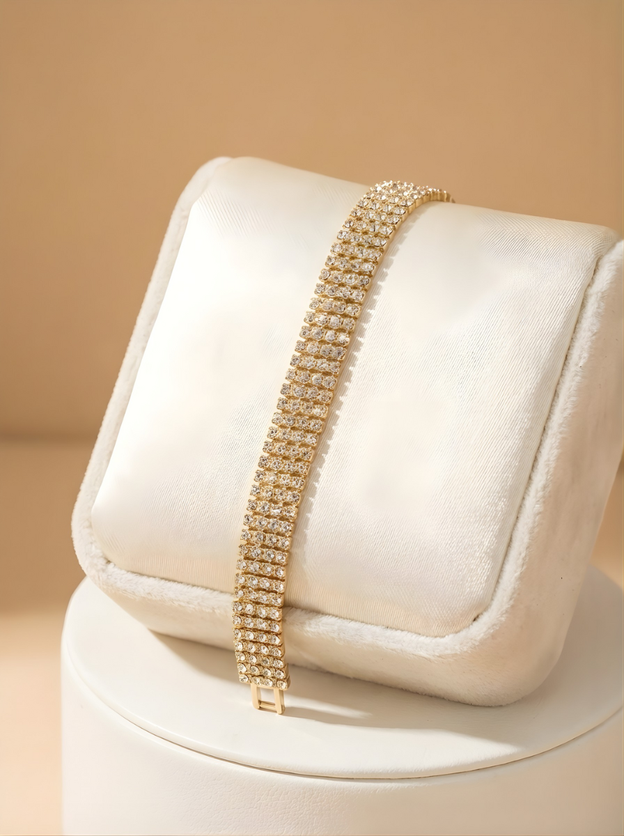 Gold bracelet on a white cushion with a beige background