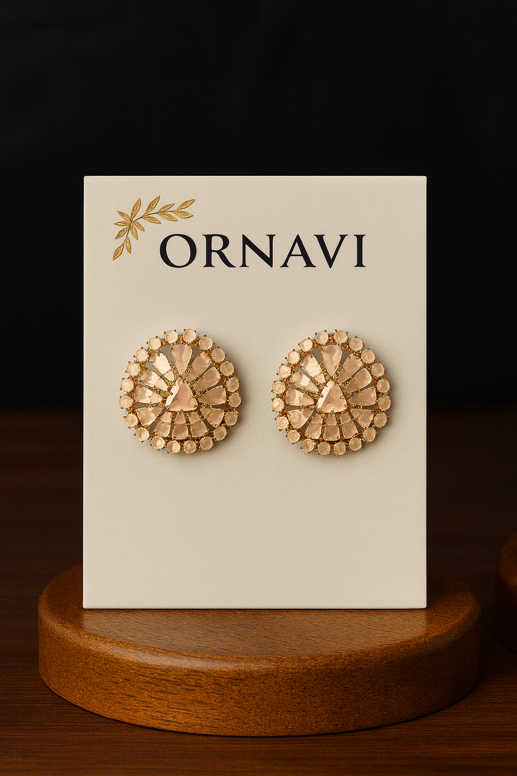 Gold earrings on a 'ORNAVI' branded card with a wooden stand.