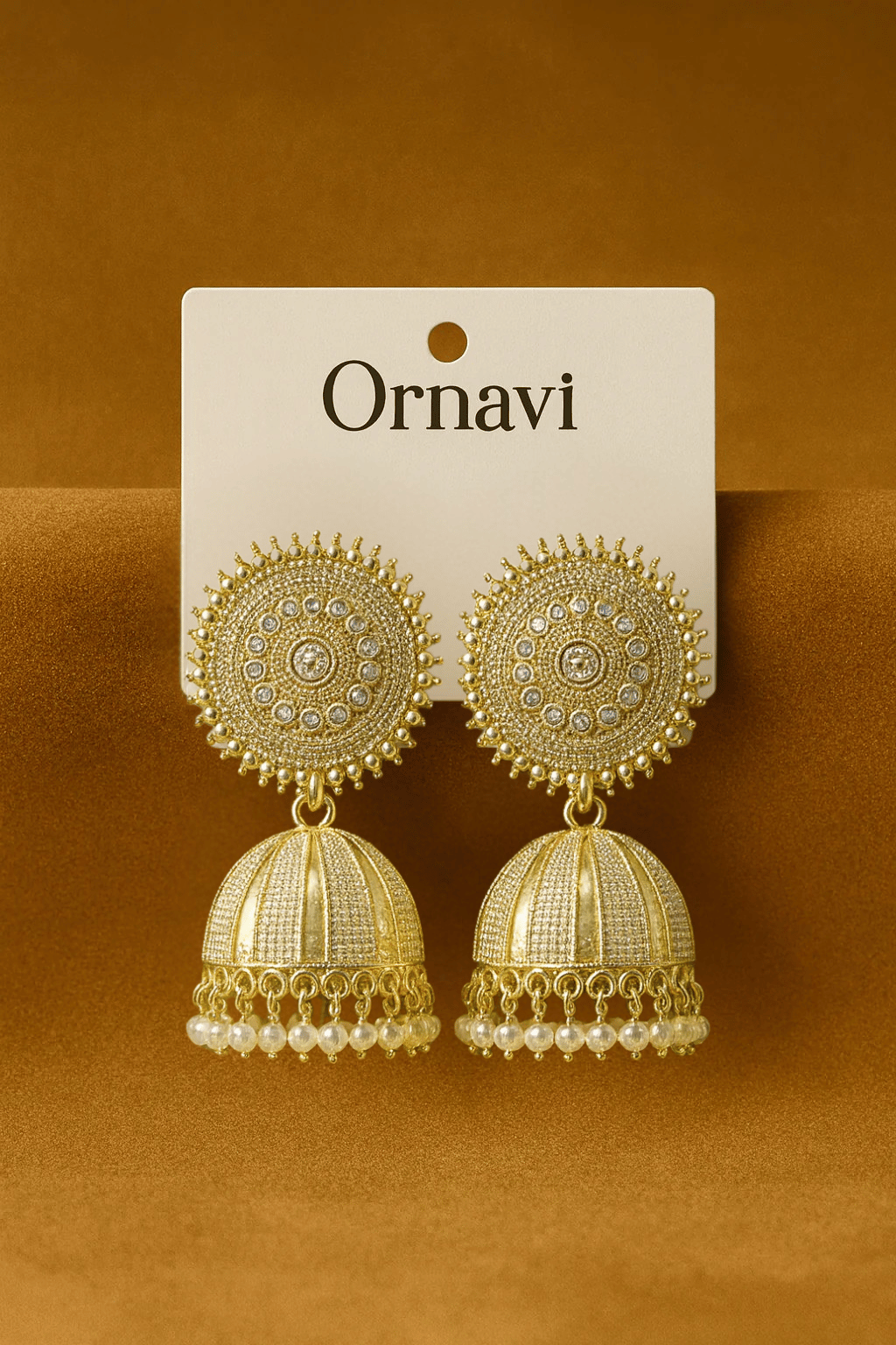 Gold earrings on a 'Ornavi' branded card against a brown background