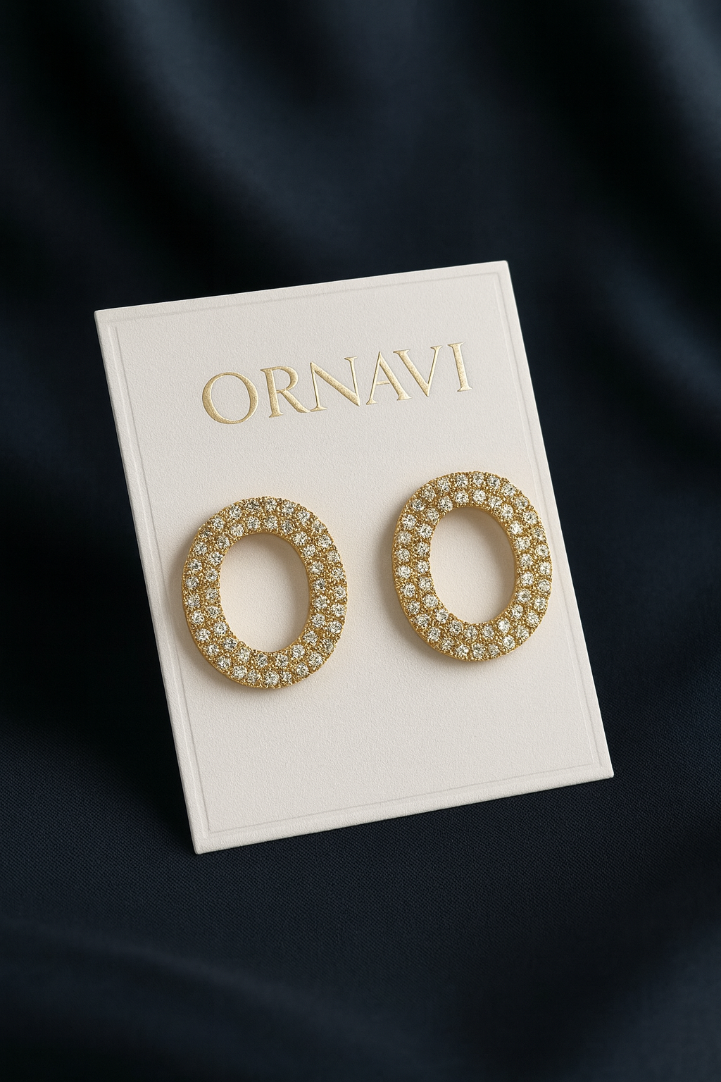Gold hoop earrings on a 'ORNAVI' branded card against a dark background