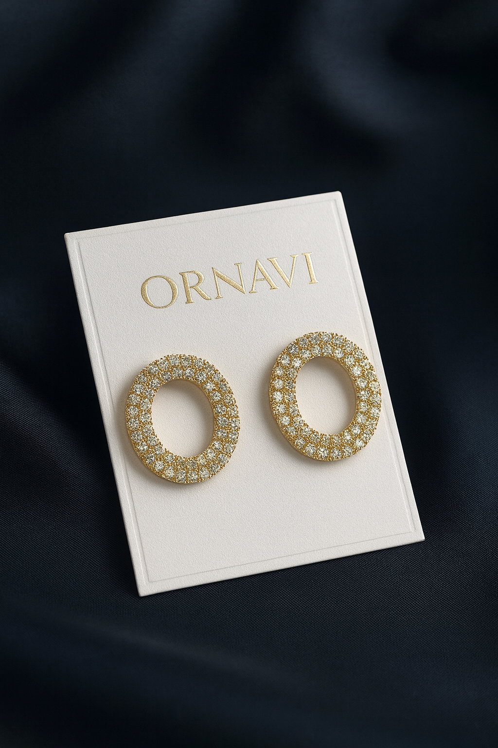 Gold hoop earrings on a white card with 'ORNAVI' branding against a dark background