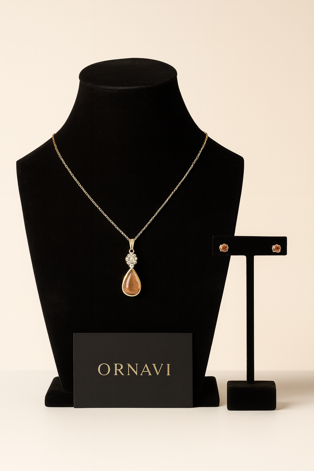Gold necklace with a pendant on a black mannequin bust, next to a black card displaying 'ORNAVI' brand name.