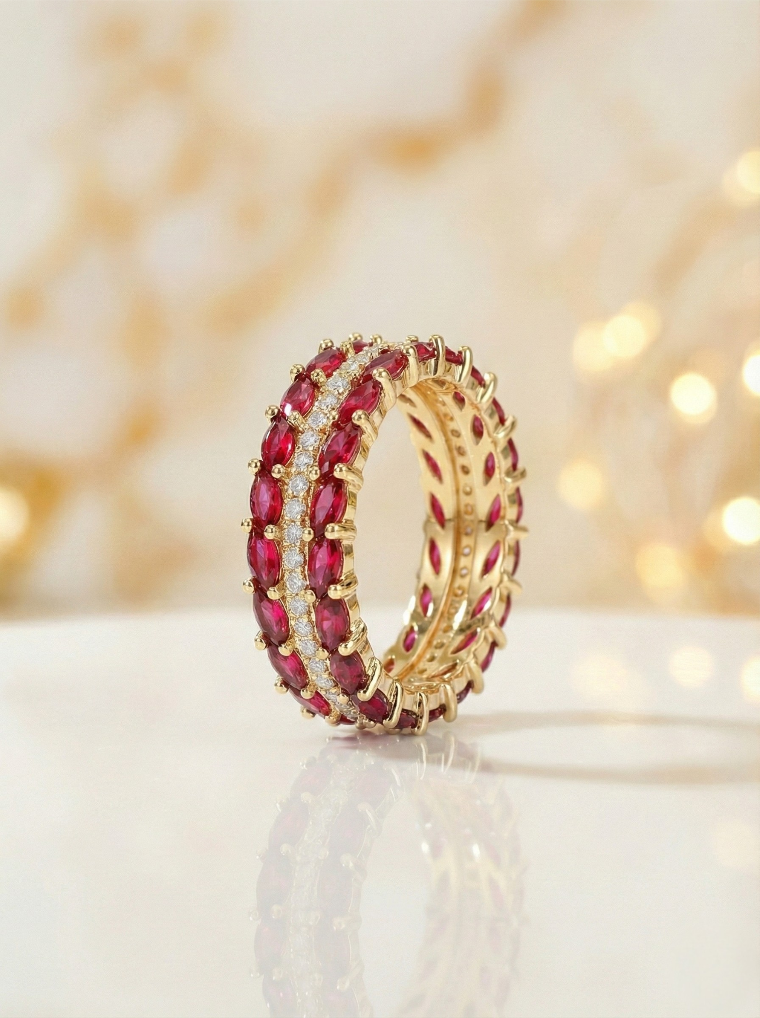 Gold ring with red gemstones on a white surface with a blurred background