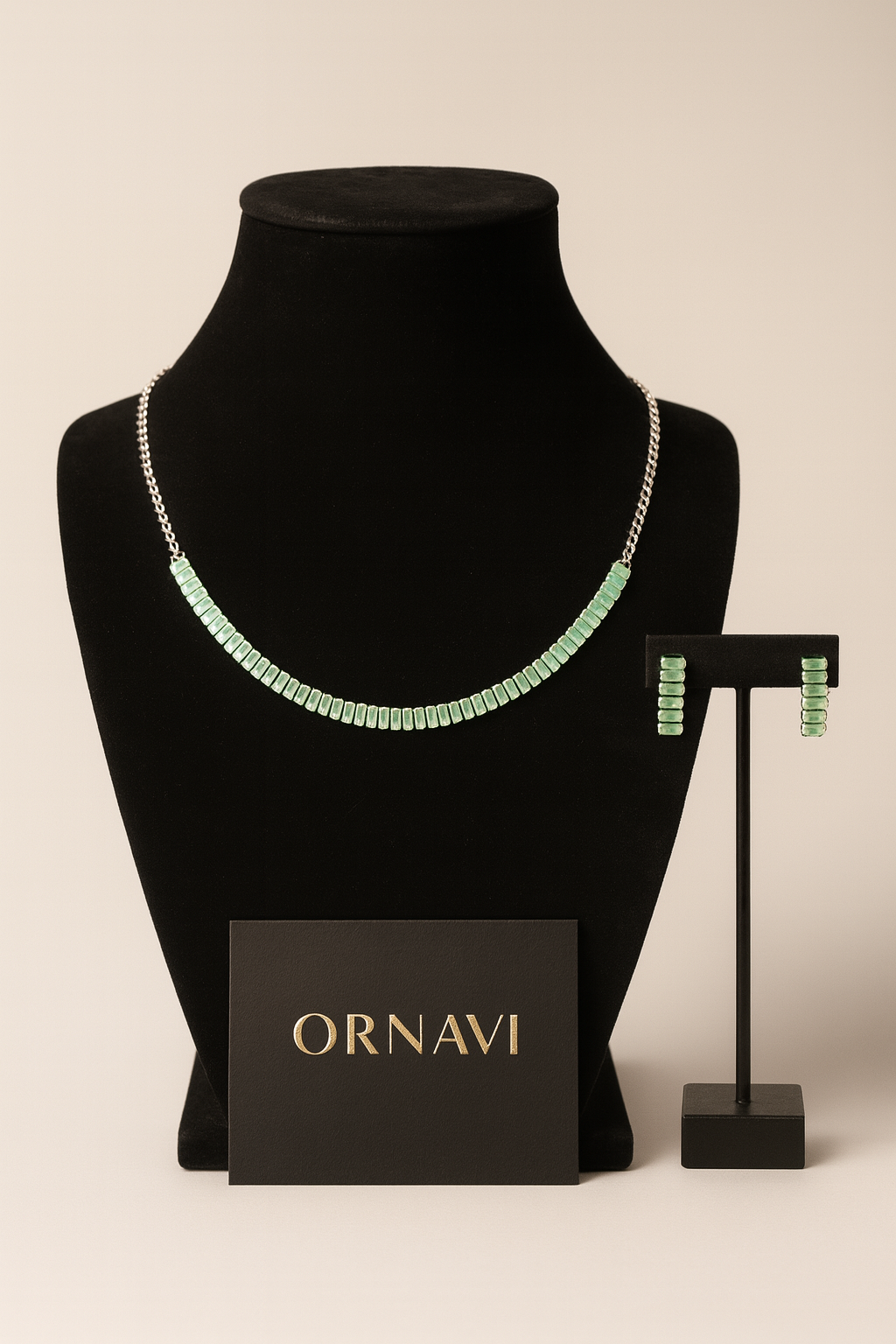 Green necklace and earrings on a black mannequin with 'ORNAVI' branding.