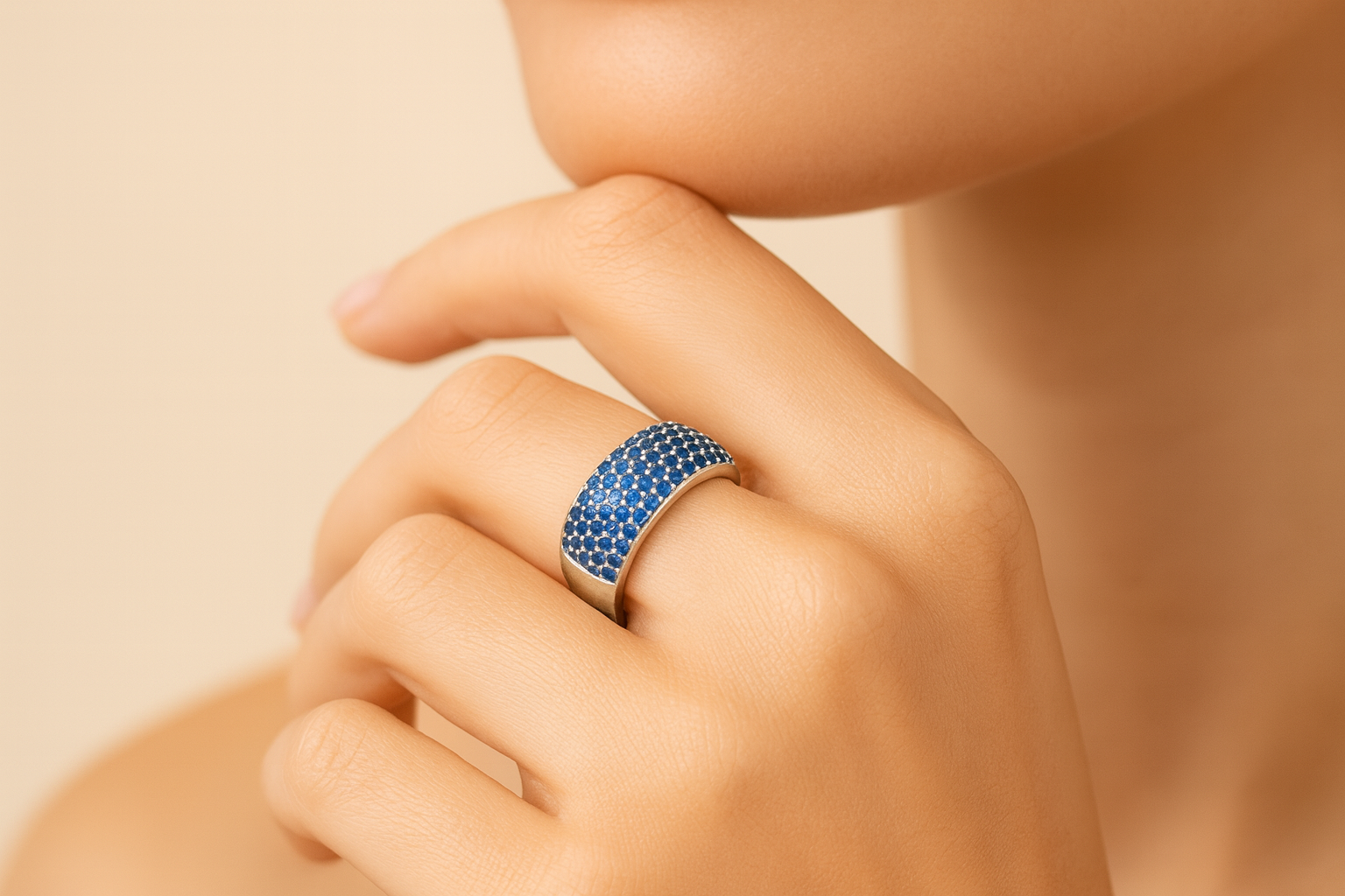 Hand wearing a blue ring on a beige background