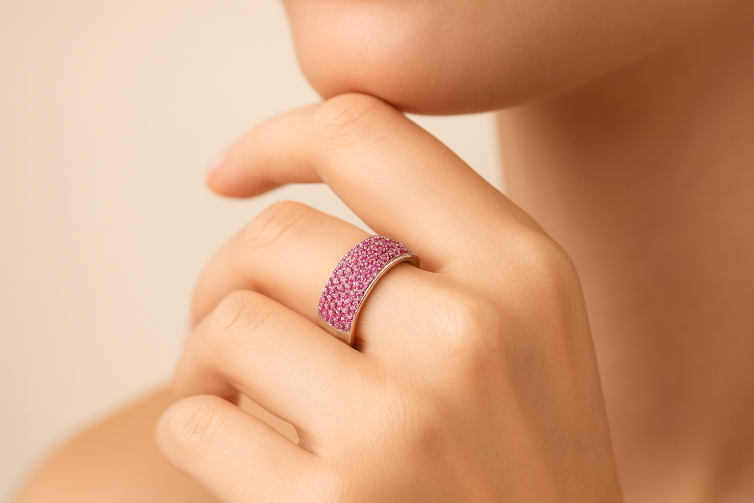 Hand wearing a pink ring on a beige background