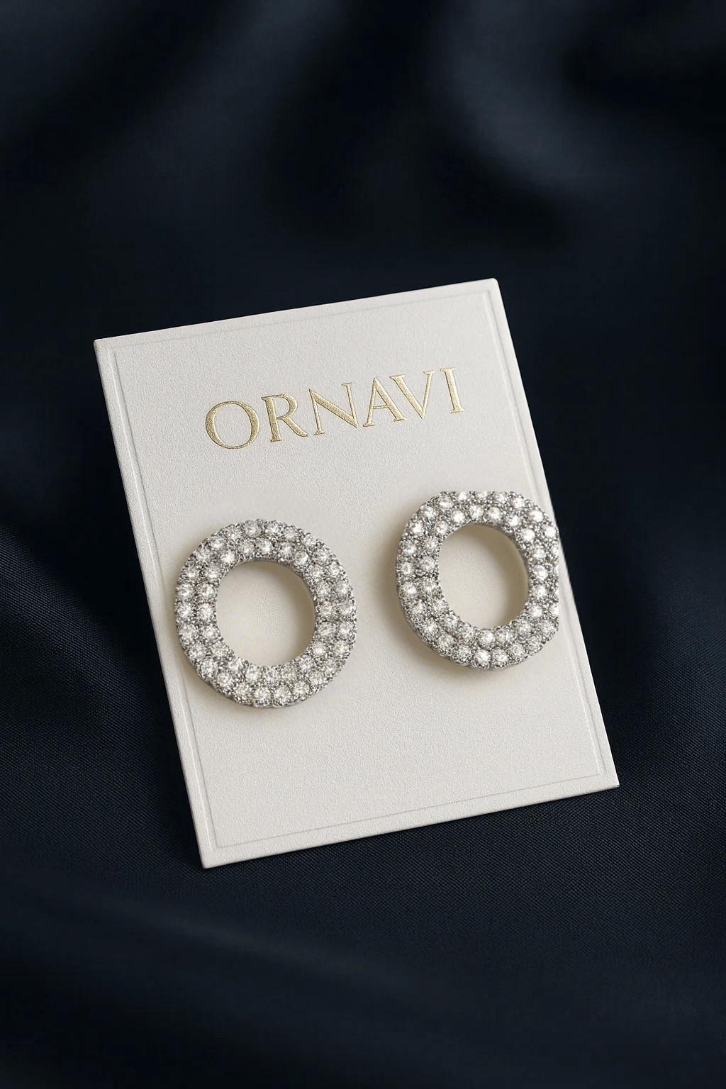 Ornate earrings on a branded ORNAVI card against a dark background
