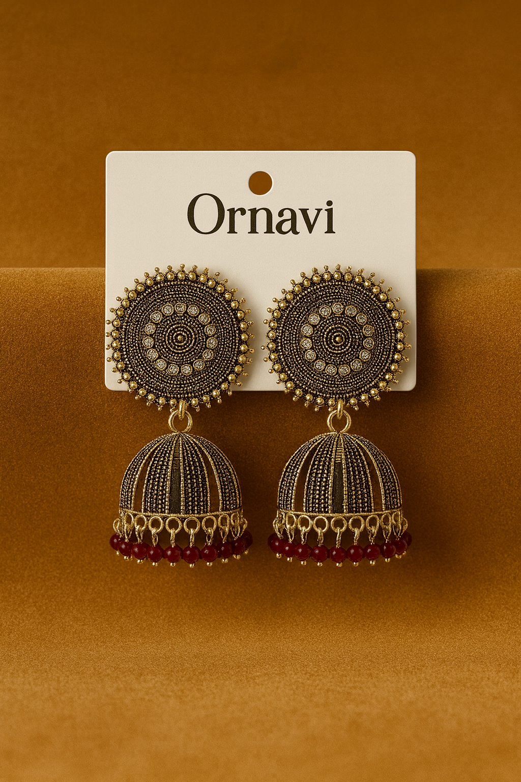Ornate earrings on a 'Ornavi' branded card against a brown background