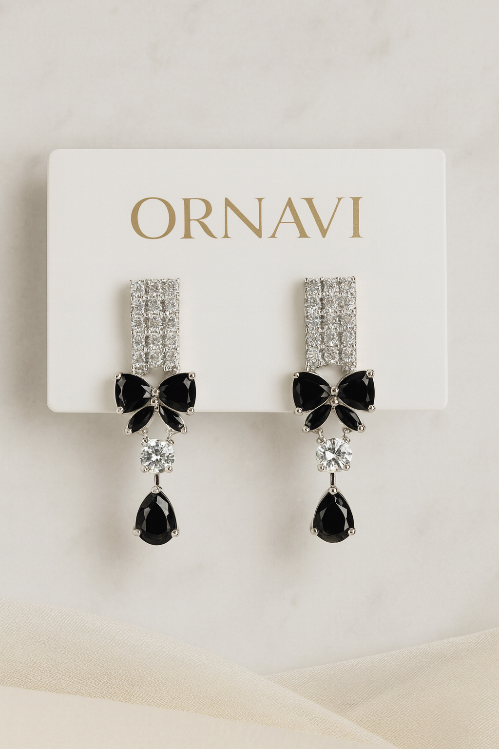 Ornate earrings with black bow and teardrop design on a white card with 'ORNAVI' branding.