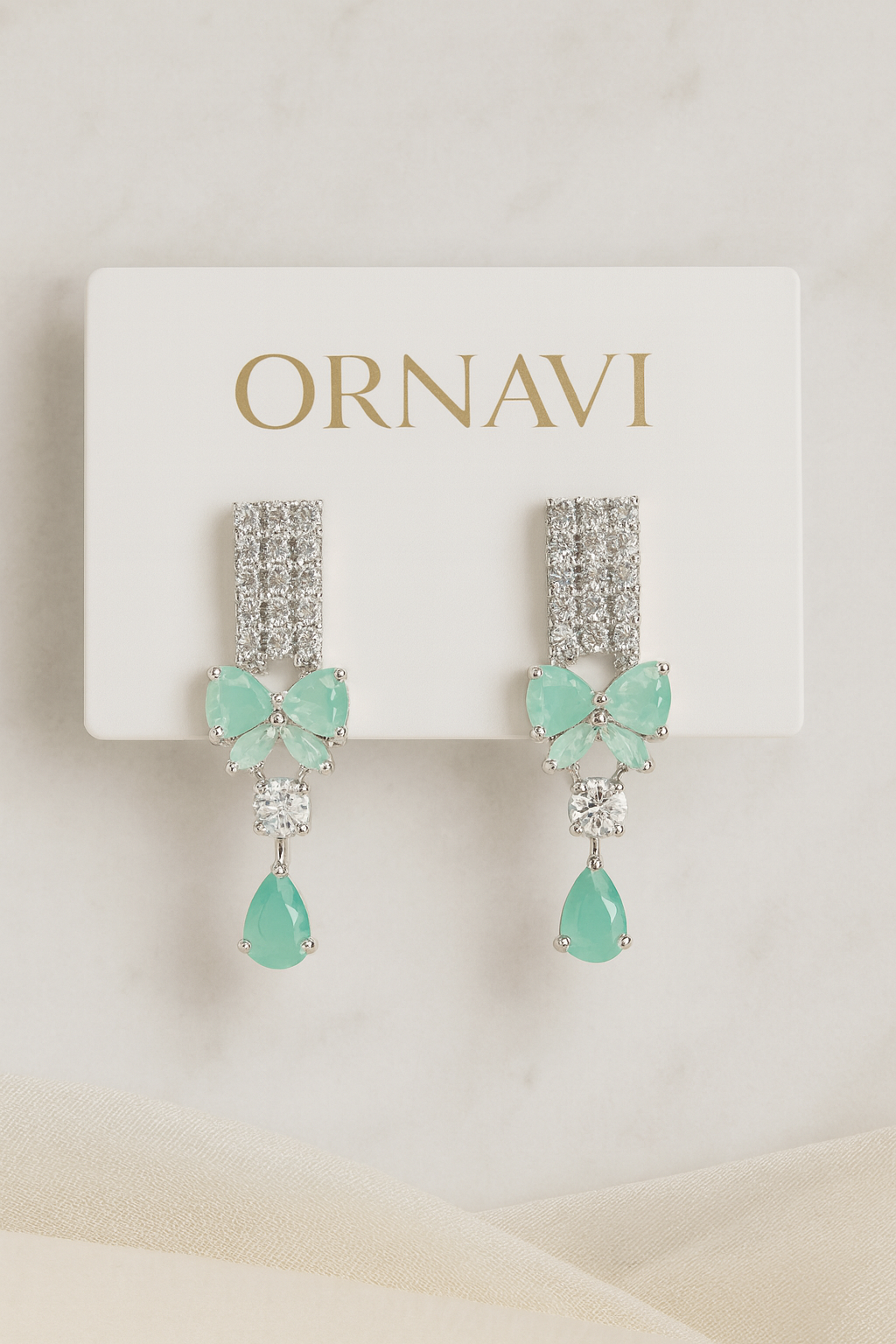 Ornate earrings with green gemstones on a 'ORNAVI' branded card.
