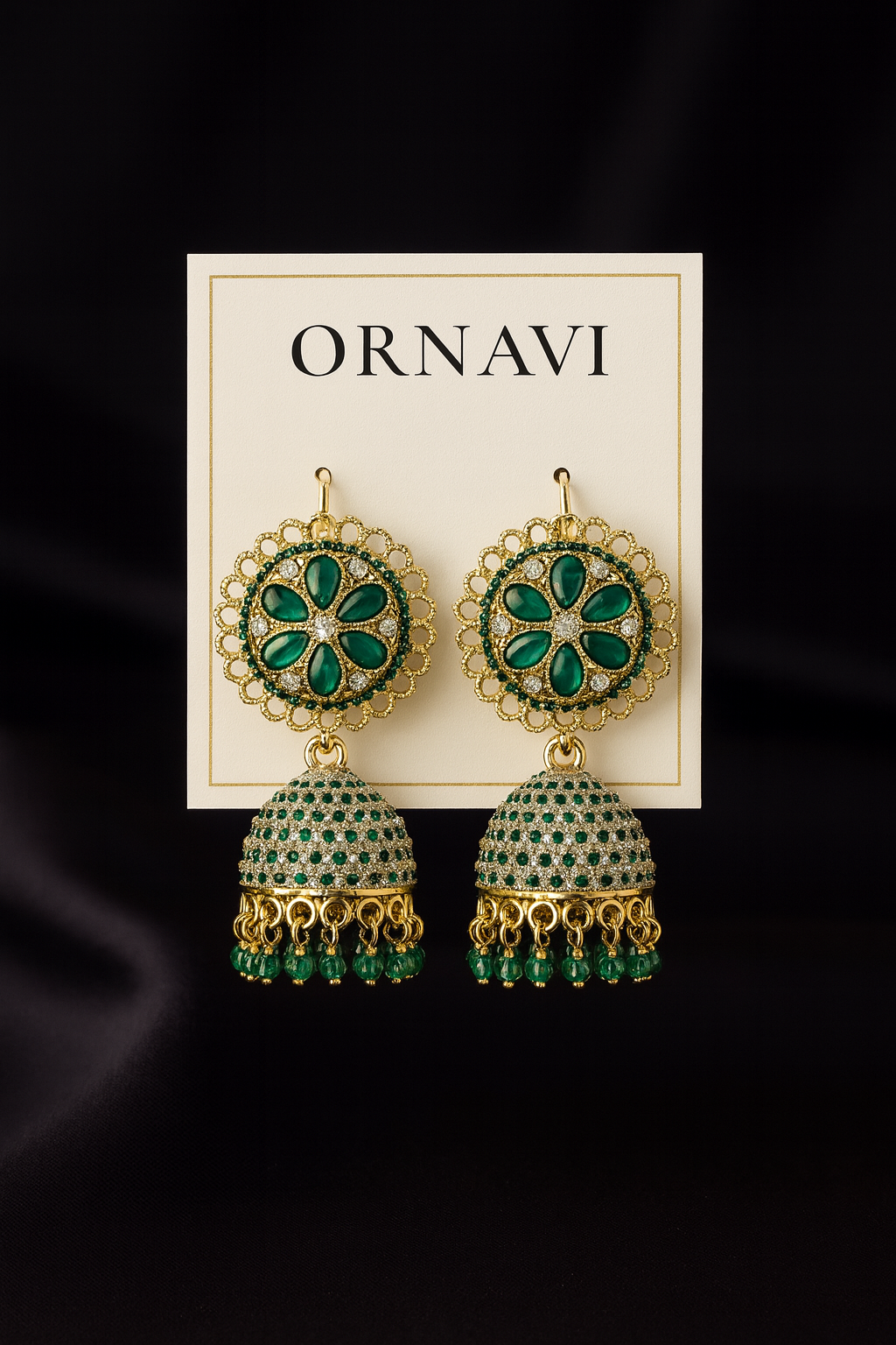 Ornate earrings with green gemstones on a 'ORNAVI' branded card against a dark background