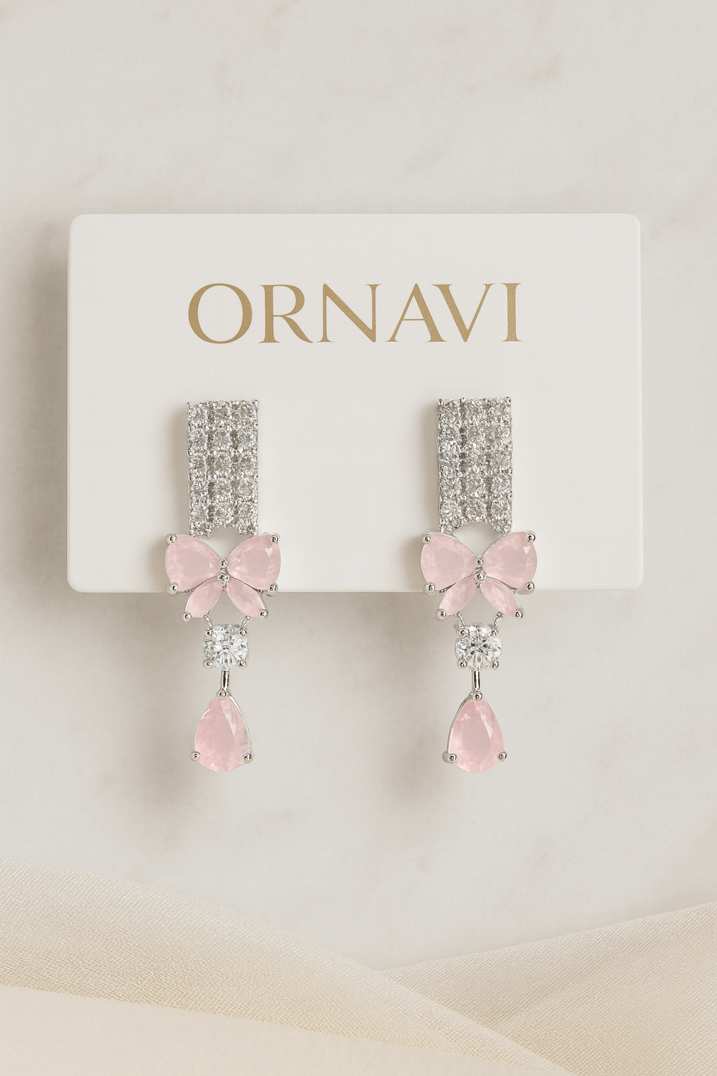 Ornate earrings with pink bows on a white card with 'ORNAVI' branding.