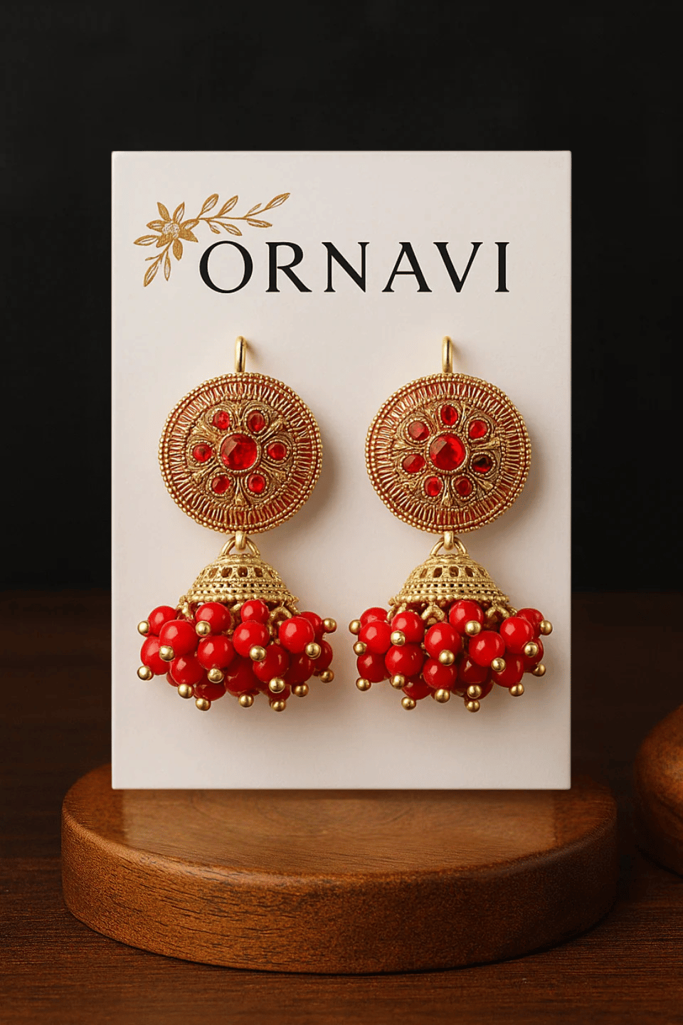 Ornate earrings with red and gold details on an ORNAVI branded card.