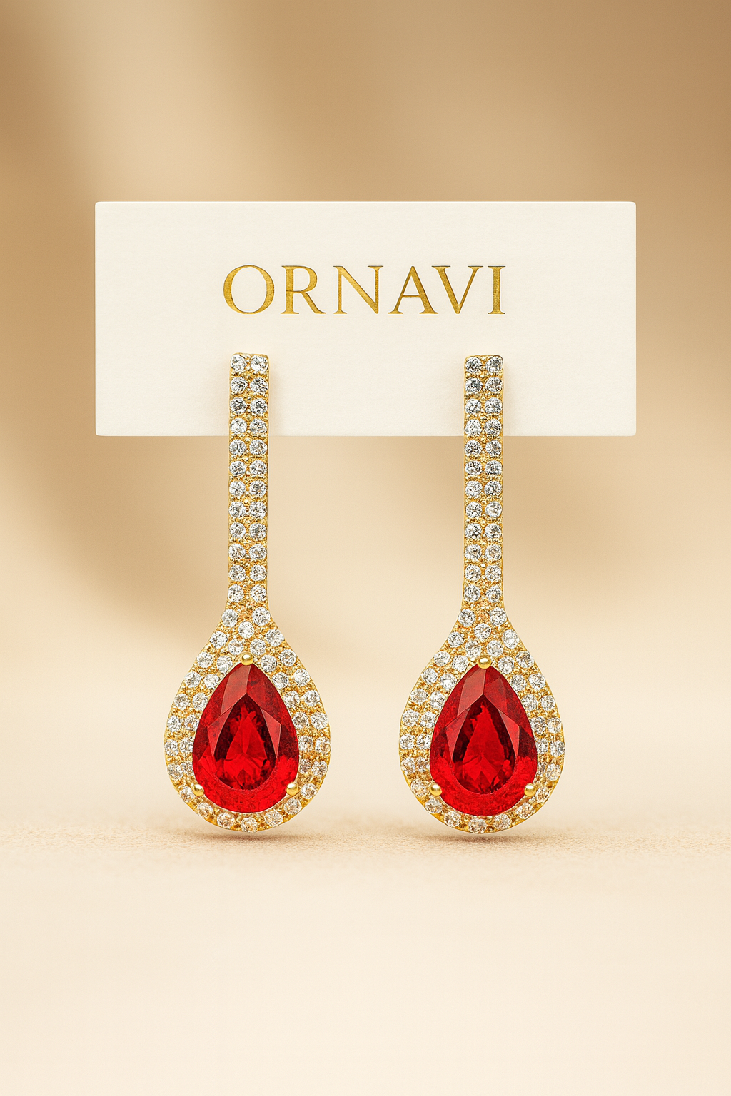 Ornate earrings with red gemstones on a beige background, featuring the brand 'ORNAVI'.