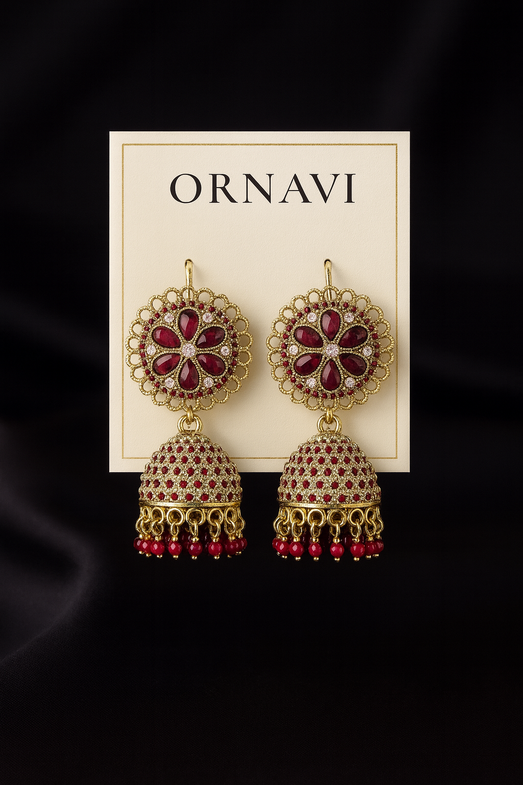 Ornate earrings with red stones on a 'ORNAVI' branded card against a black background
