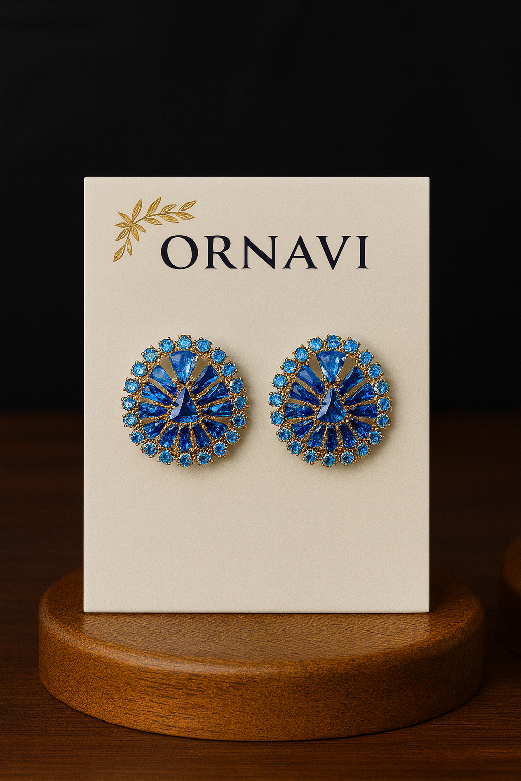 Pair of blue earrings on a 'ORNAVI' branded card with a wooden stand.
