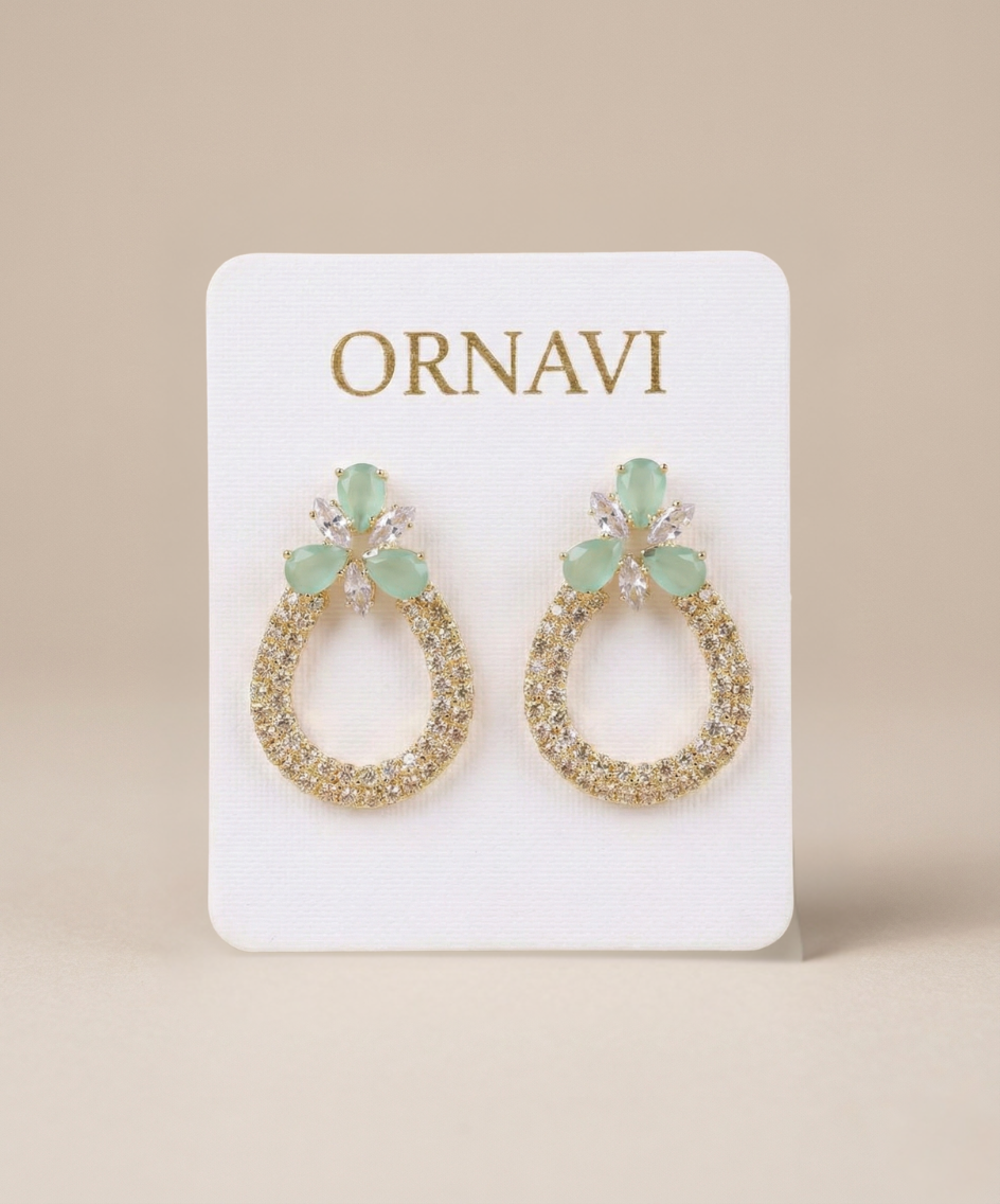 Pair of earrings on a 'ORNAVI' branded card against a beige background