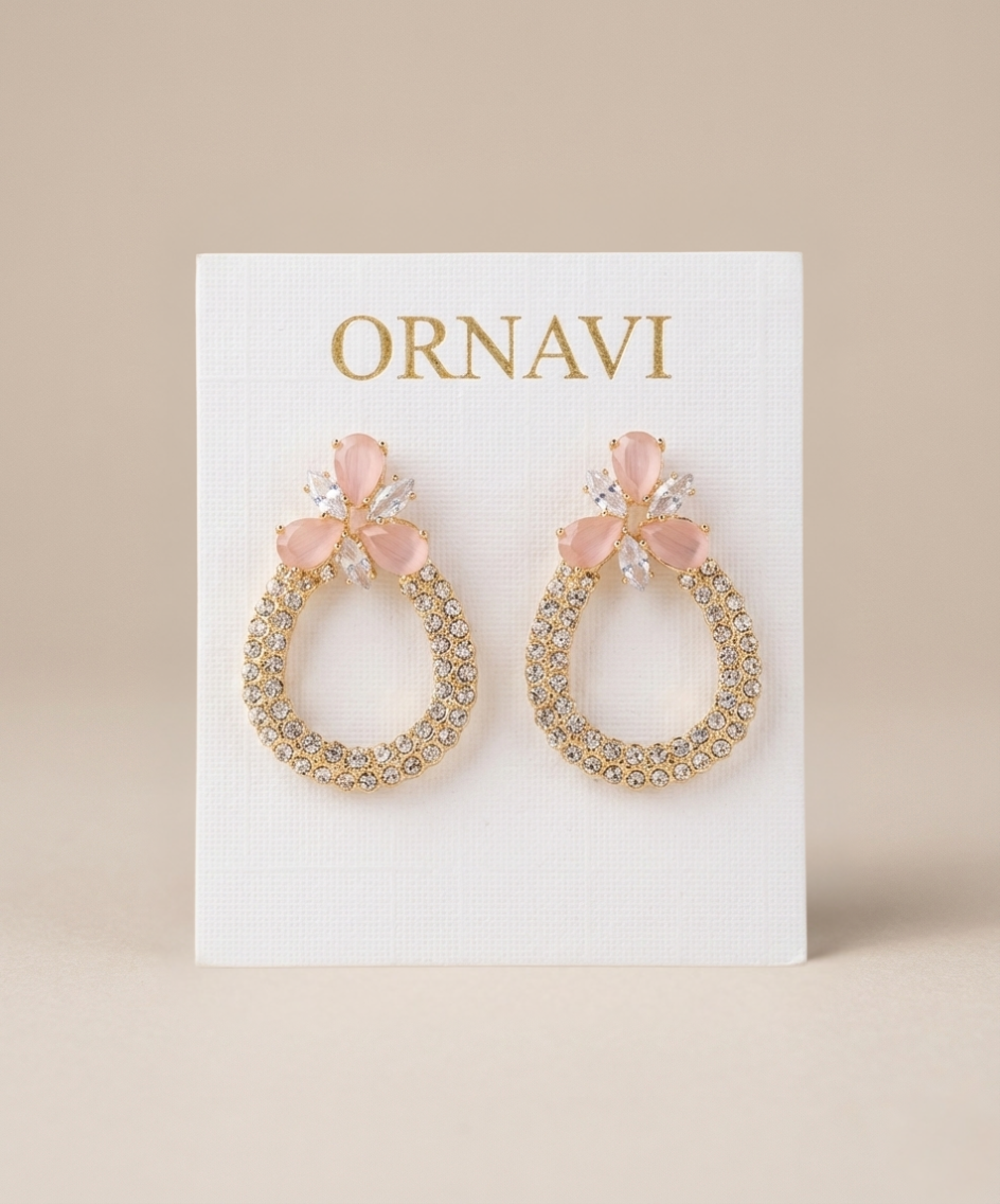Pair of gold hoop earrings with pink bows on a white card with 'ORNAVI' branding.