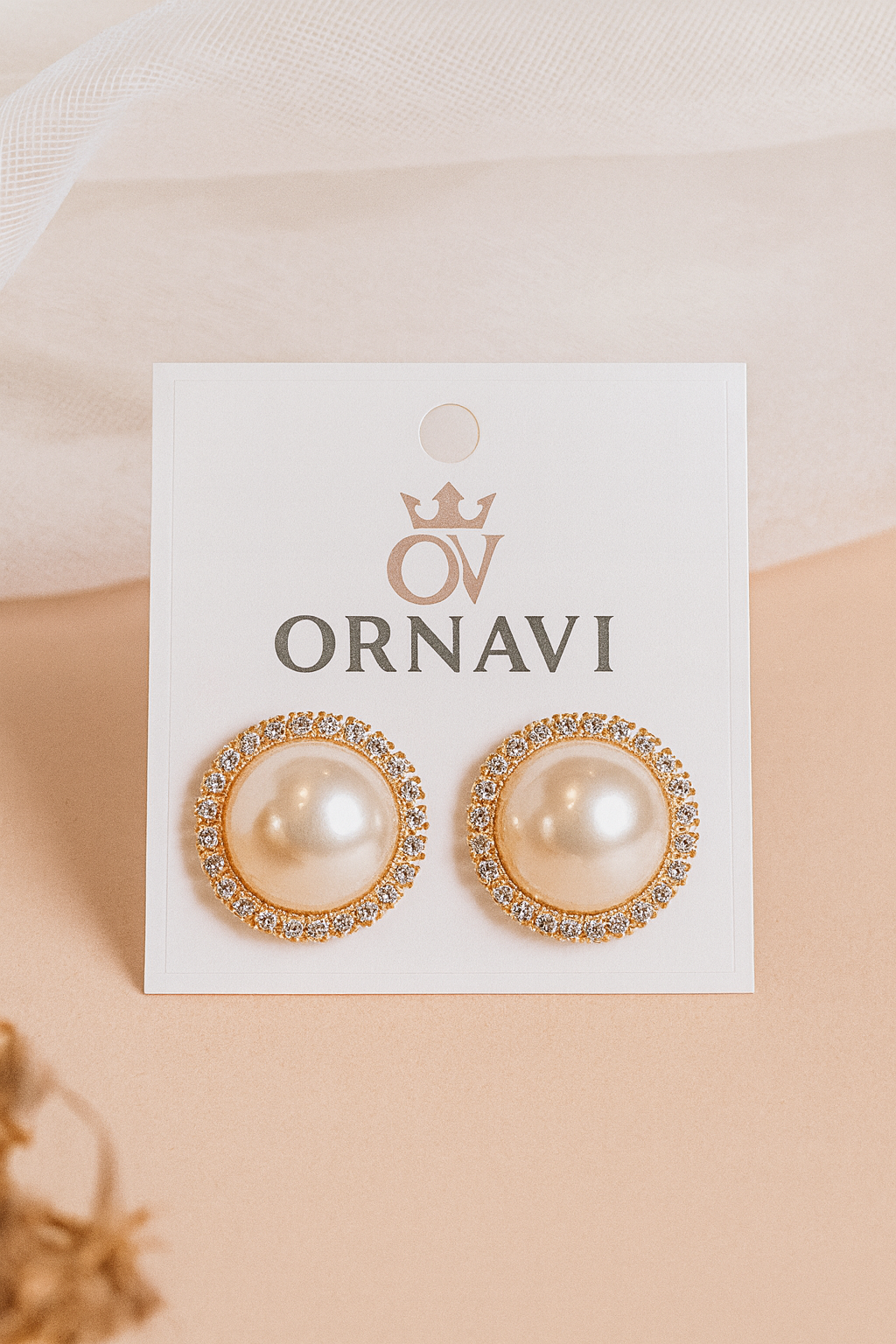 Pair of pearl earrings on a white card with 'Ornavi' branding on a beige background