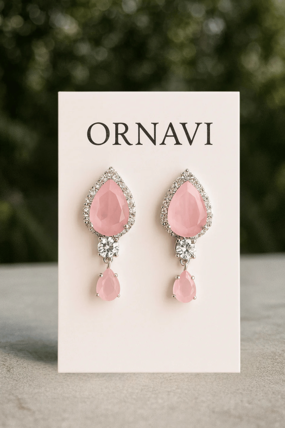 Pink earrings on a 'ORNAVI' branded card with a blurred green background