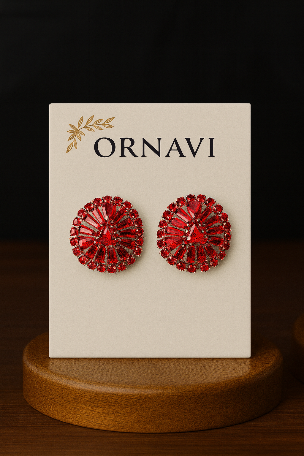 Red earrings on an ORNAVI branded card with a wooden stand.