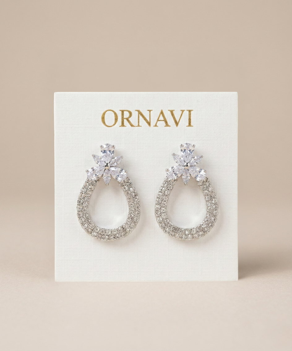 Silver earrings on a white card with 'ORNAVI' branding against a beige background