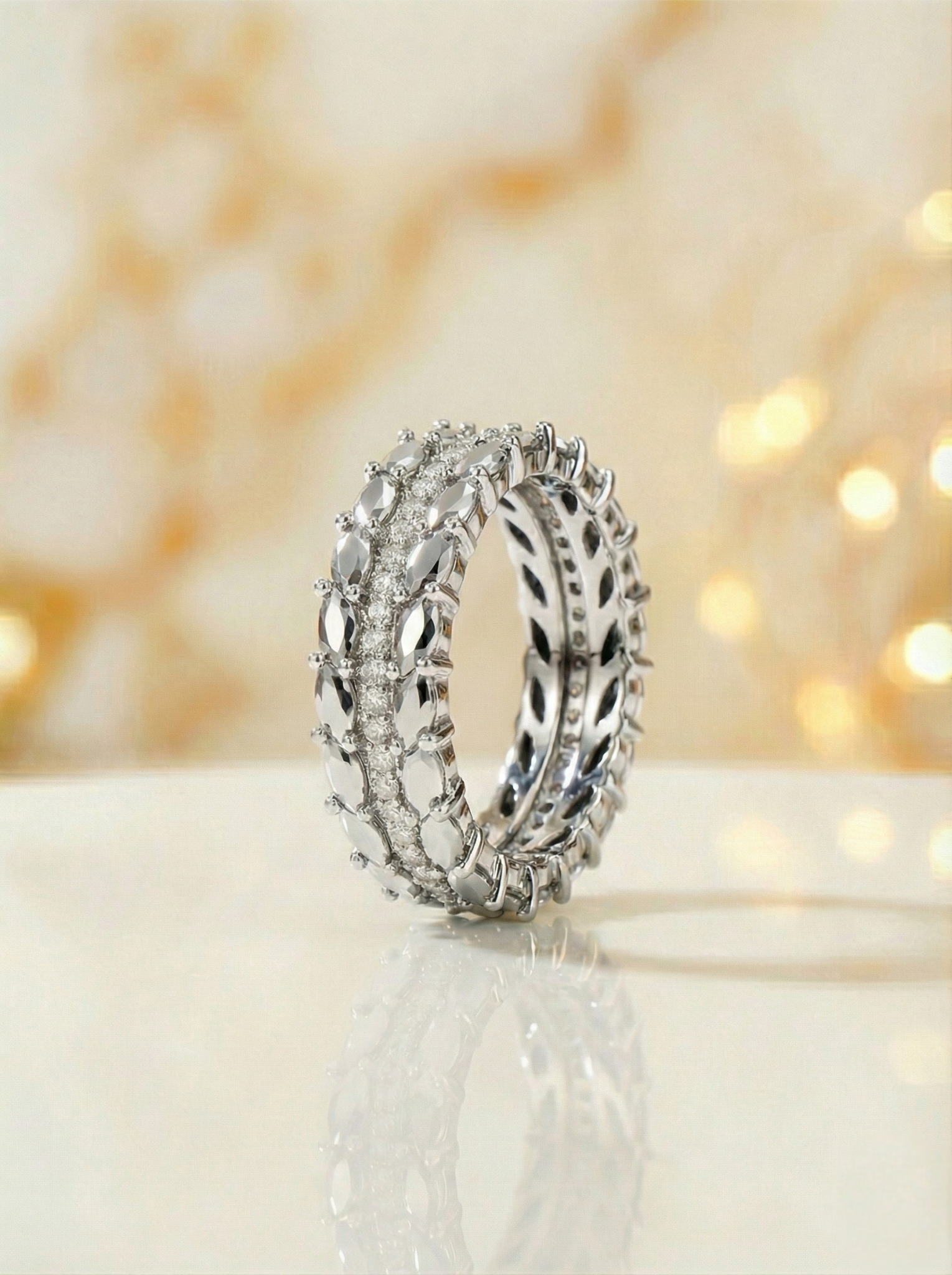 Silver ring with intricate design on a white surface with a blurred light background