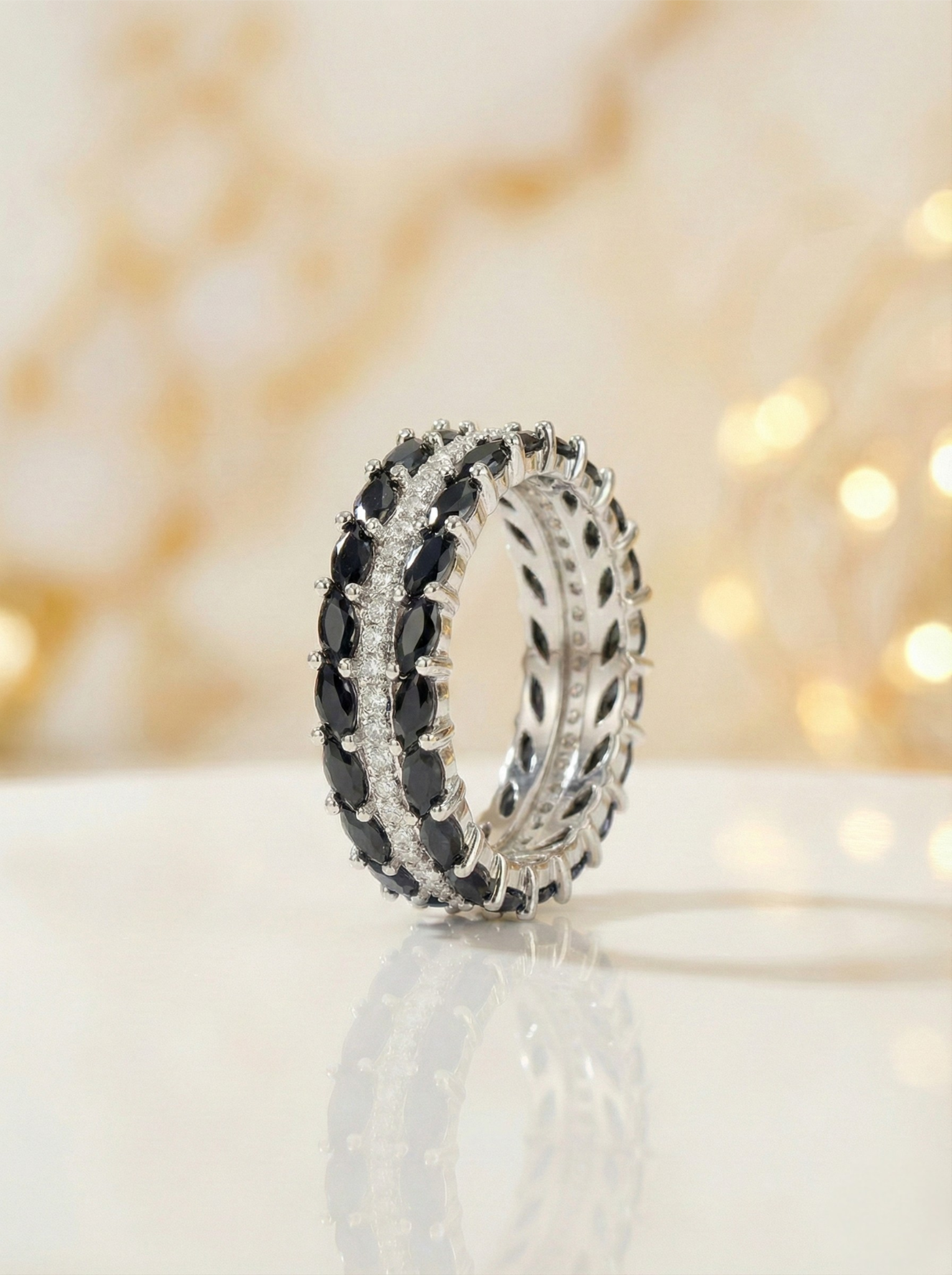 Two silver rings with black gemstones on a white surface with a blurred light background