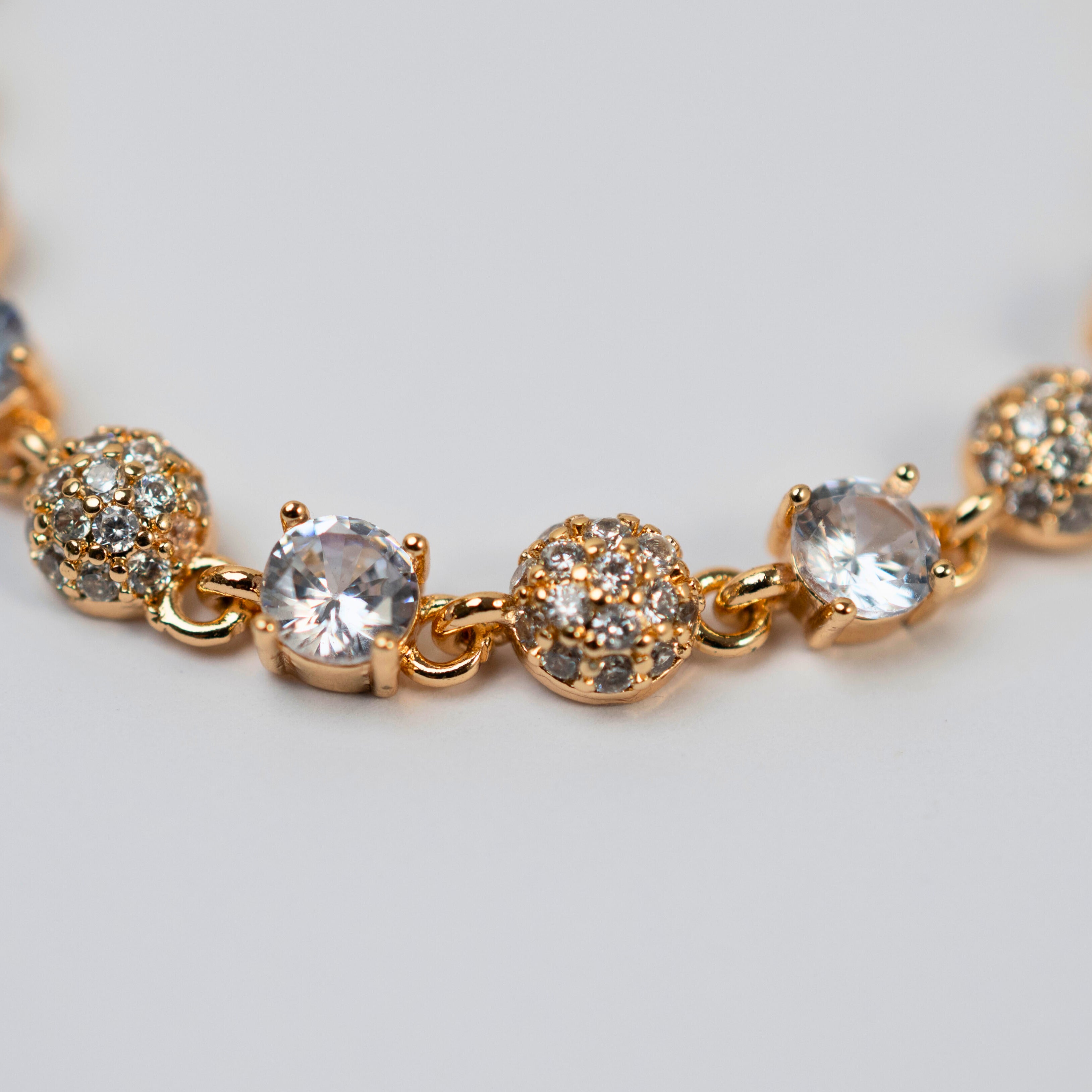 Gold bracelet with clear stones on a light gray background